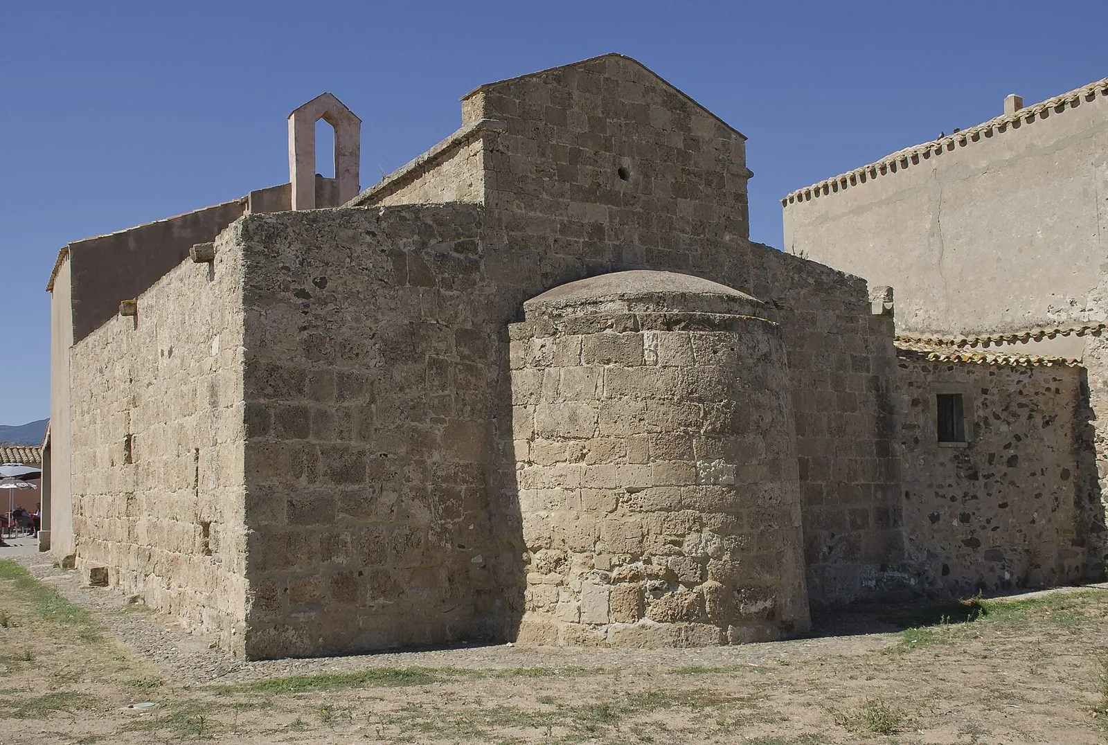 L'abside semicircolare e i muri in blocchi di pietra della chiesa di Sant'Efisio a Nora, sotto un cielo azzurro